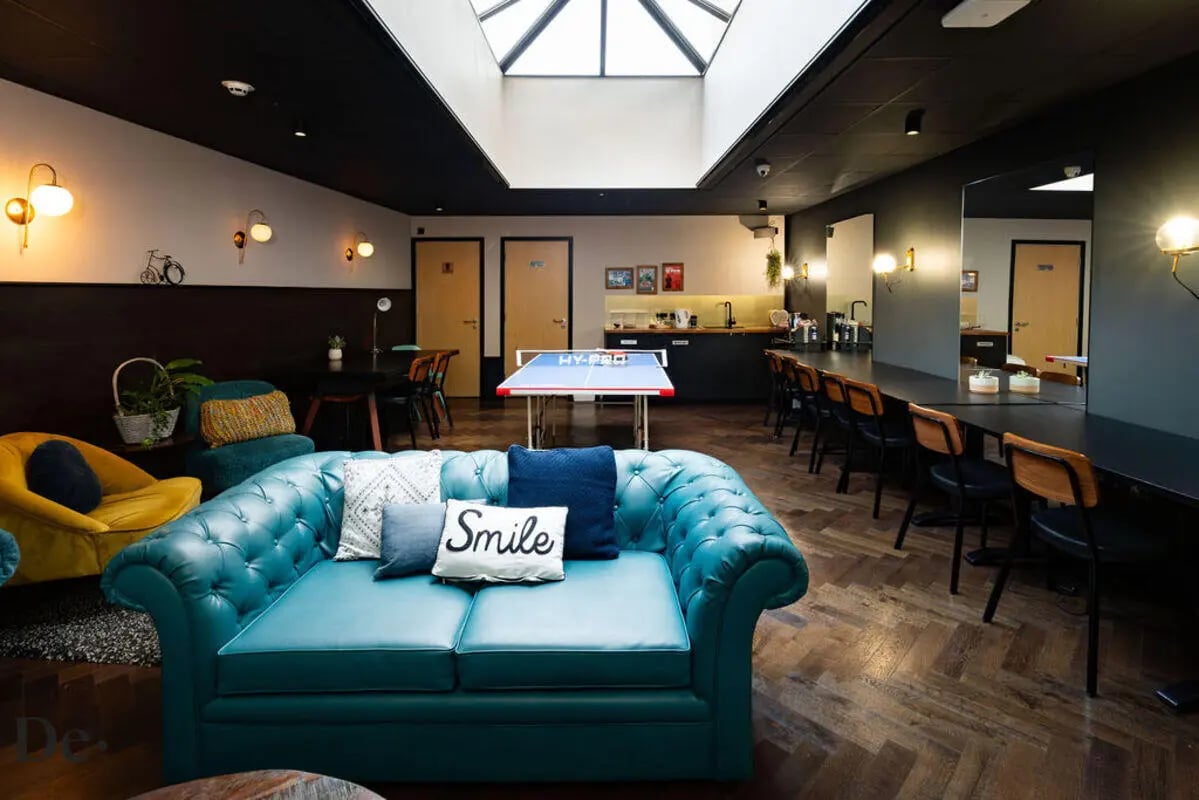 Turquoise couch ping pong table kitchen area living room at Castle Hill in Cambridge Student Accommodation
