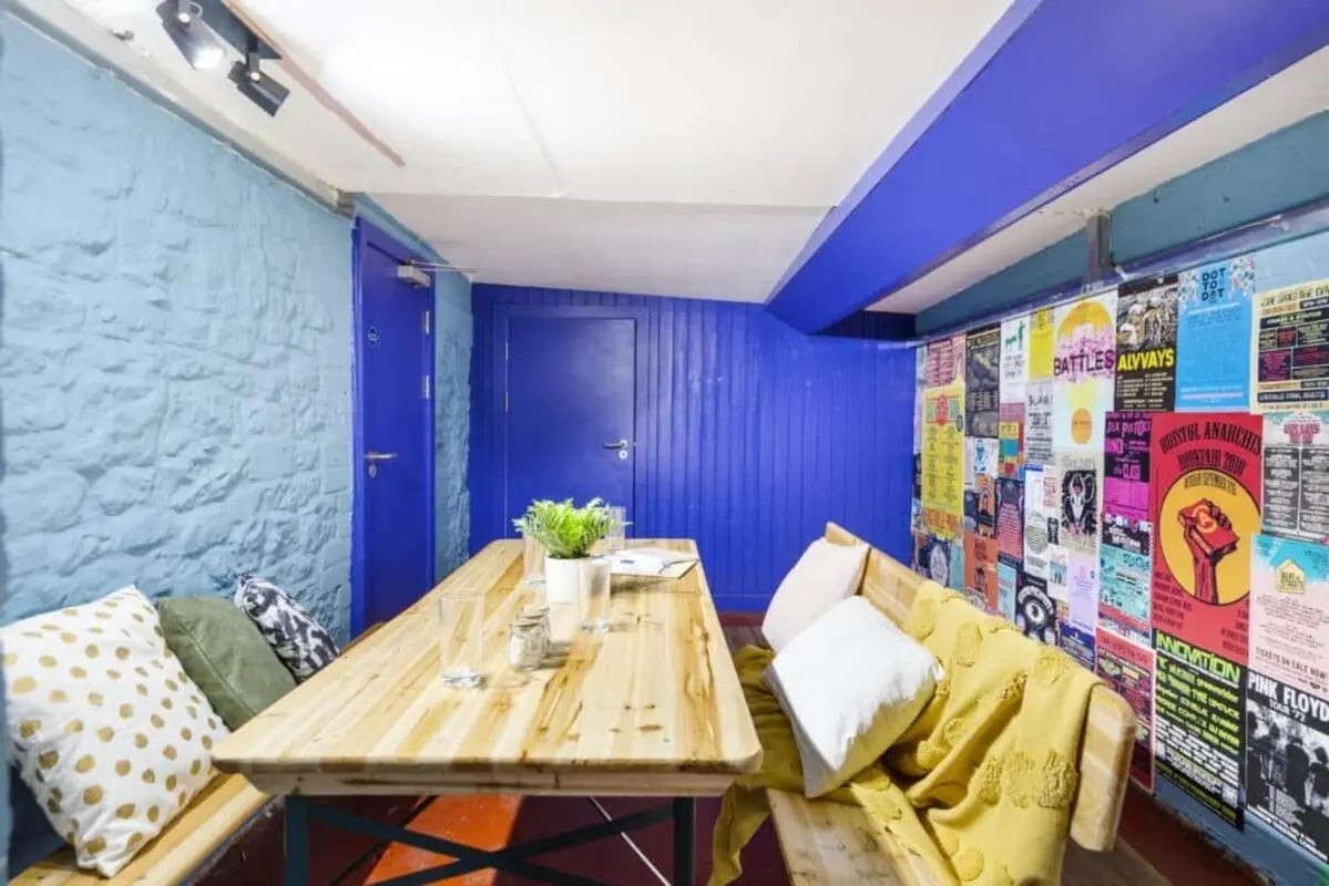 Wooden table benches posters and cushions communal area at Tamarillo House in Bristol Student Accommodation
