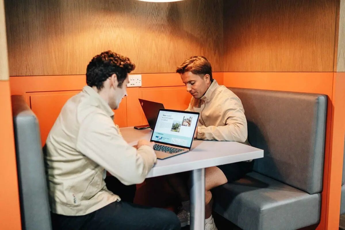 Two students working on laptops in a study booth at Caledon Court in Aberdeen Student Accommodation
