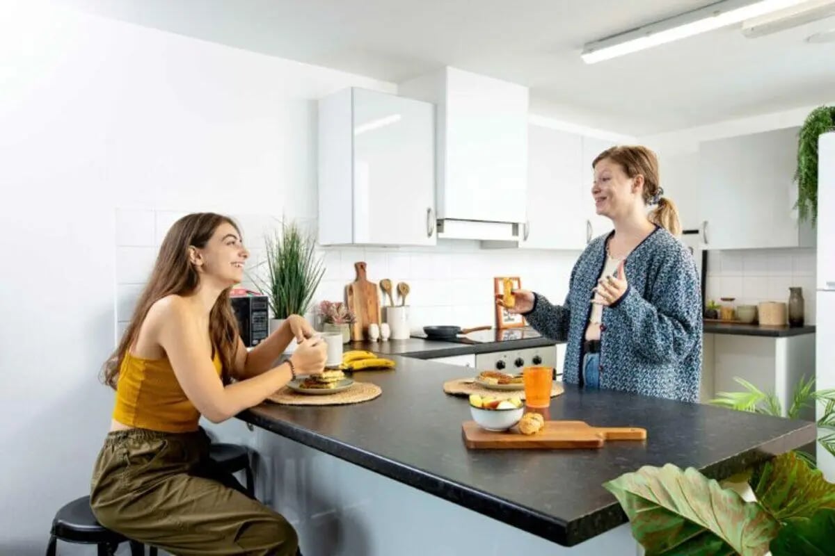 Two women eating breakfast at kitchen counter kitchen at North Court in Cardiff Student Accommodation