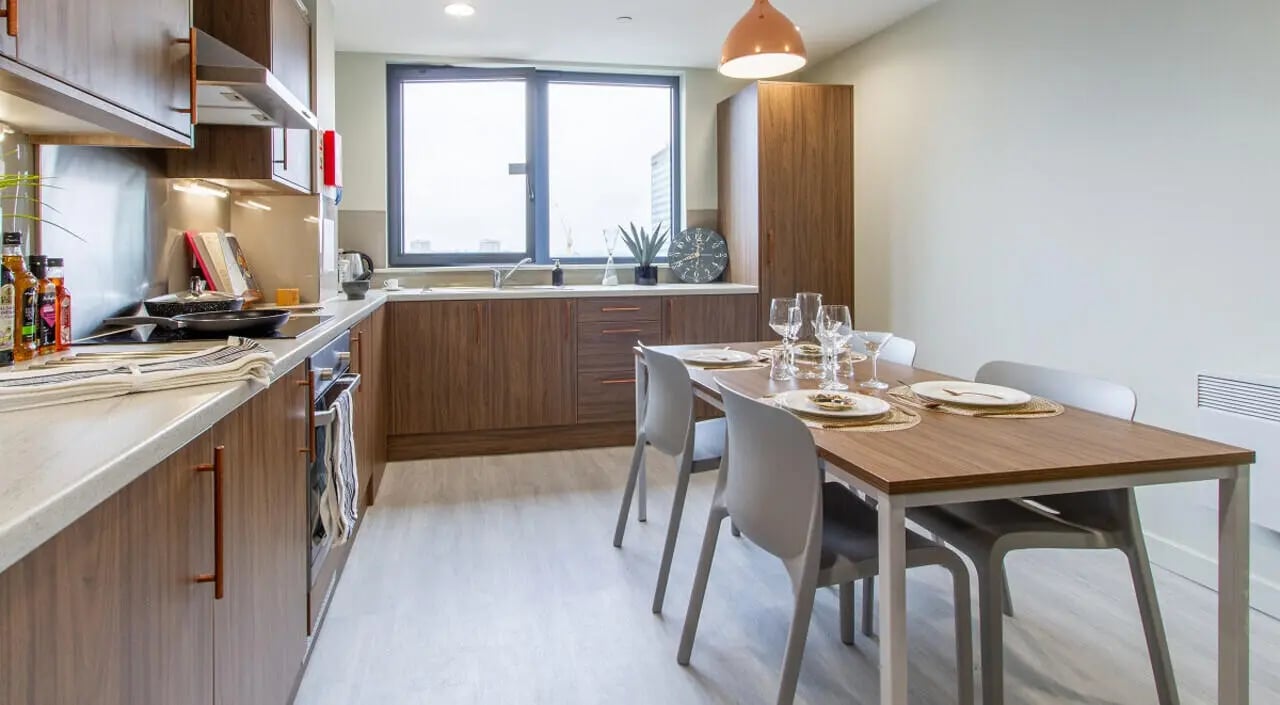 Wood cabinets dining table place settings chairs kitchen at The Toybox in Birmingham Student Accommodation