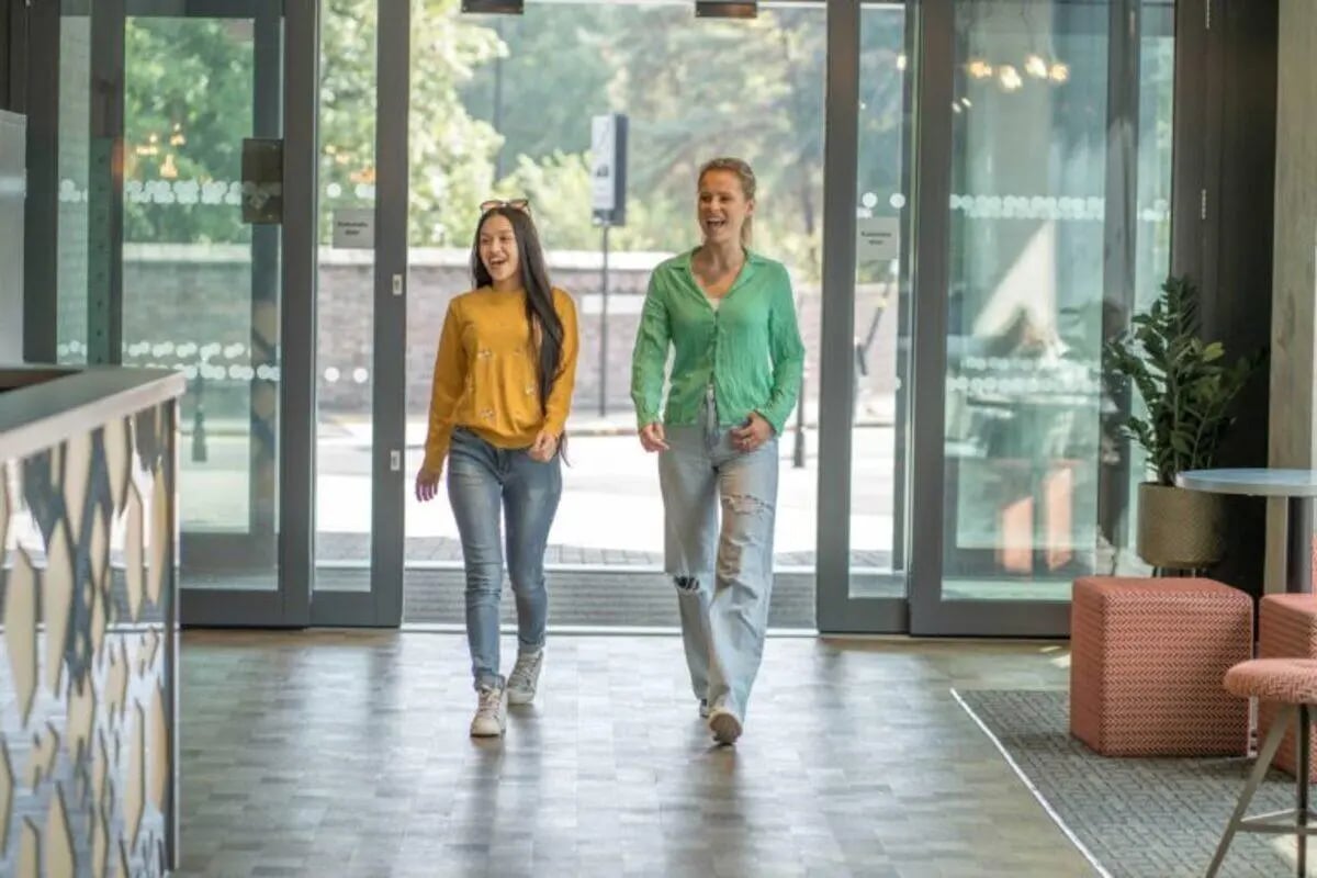 Two women walking through modern reception area entrance at The Toybox in Birmingham Student Accommodation