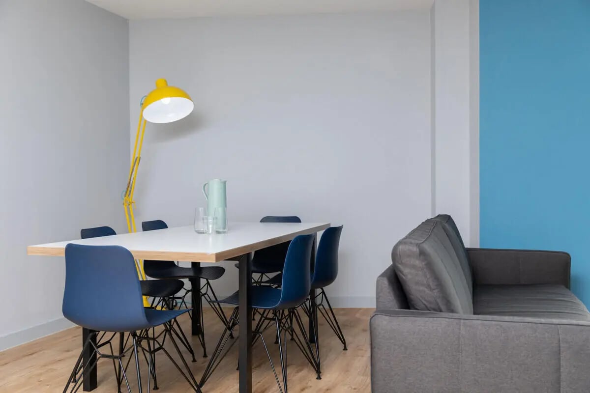 Table chairs pitcher glasses lamp sofa living area at West Wing in Cardiff Student Accommodation