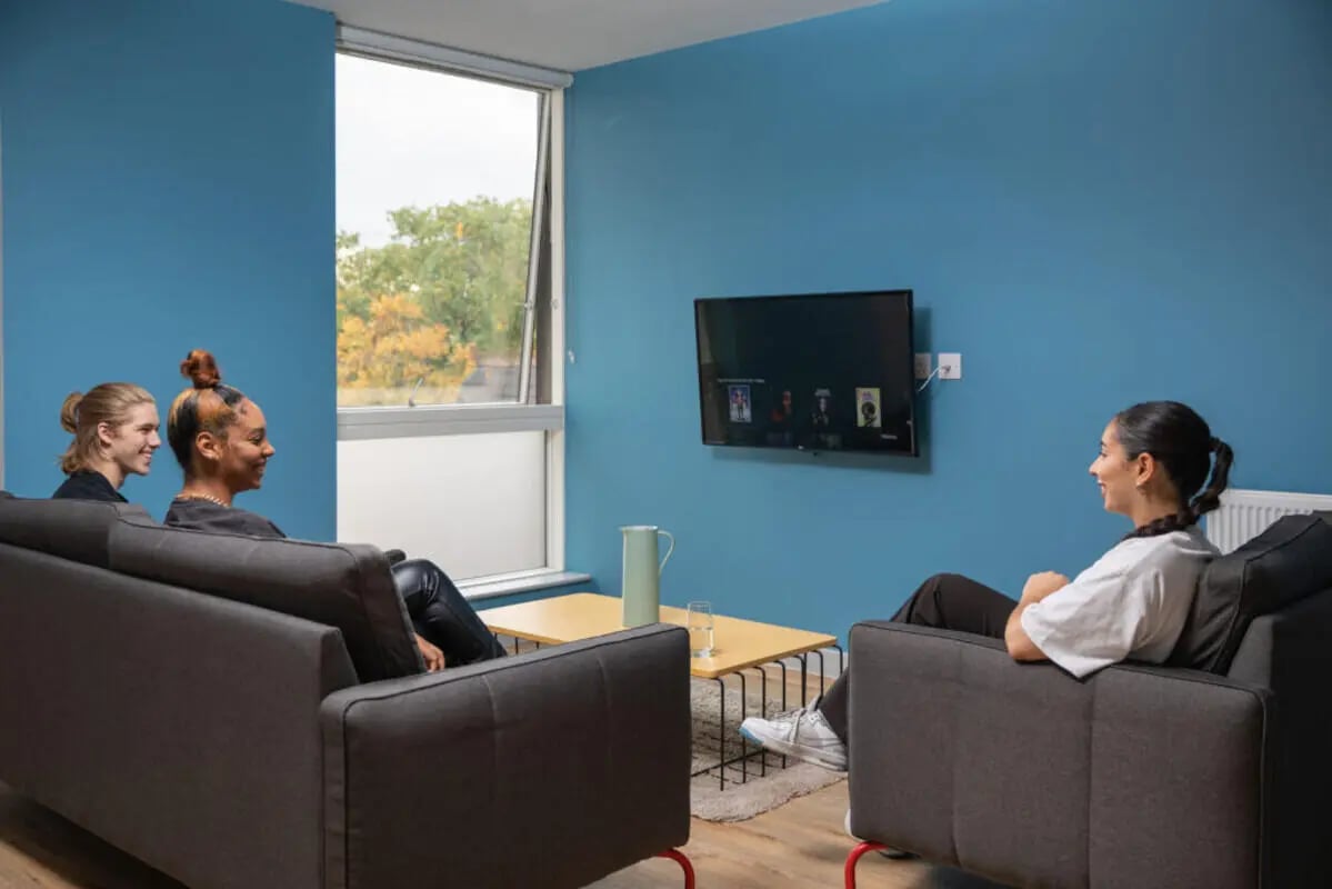 People relaxing on sofas watching TV living room at West Wing in Cardiff Student Accommodation