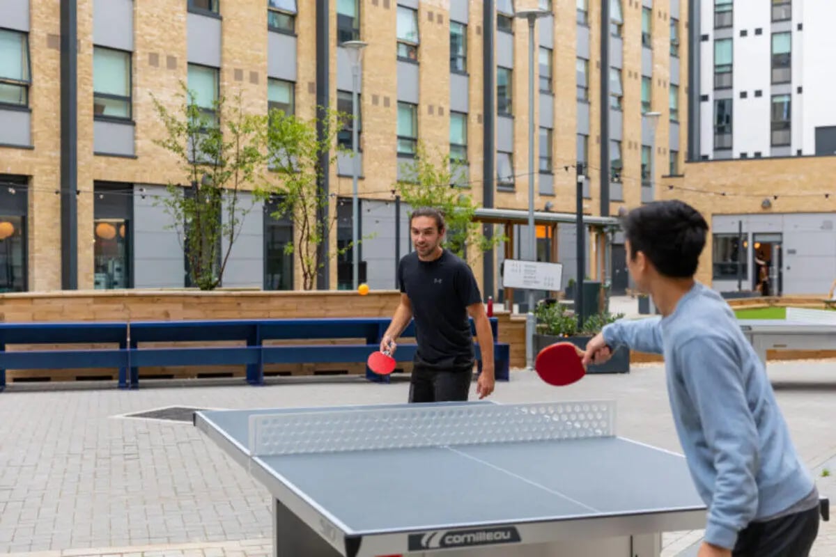 Two students playing table tennis outside exterior at The Depot in Bath Student Accommodation