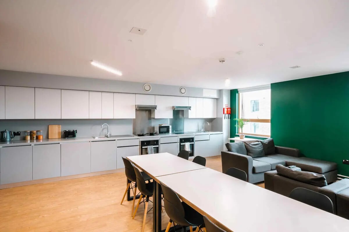 Kitchen area with white cabinets grey counters and living room living area at The Depot in Bath Student Accommodation
