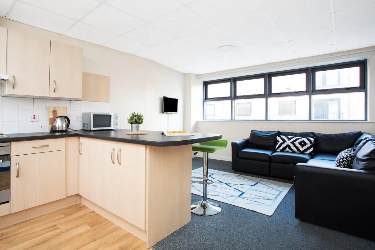 Kitchen counter with microwave sofa and bar stool living room at The Grange Leicester in Leicester Student Accommodation