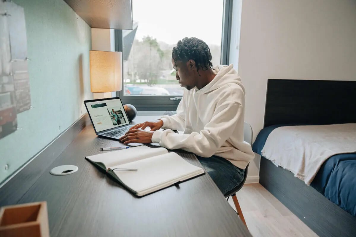 Student with laptop and notebook bedroom study area at Avon Studios in Bath Student Accommodation