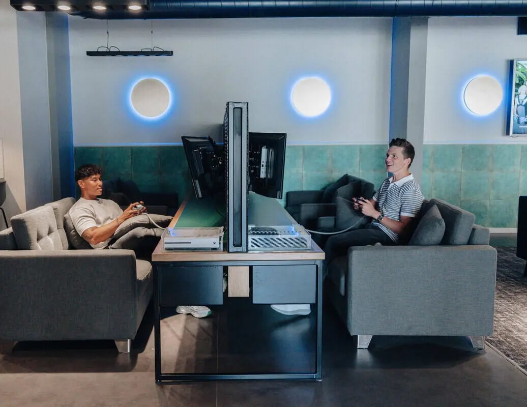Two students playing video games on sofas gaming area at Alma Court in Canterbury Student Accommodation