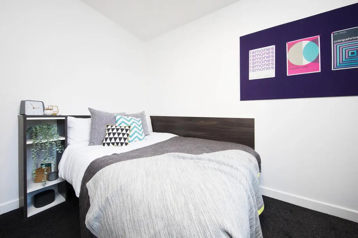 Bed with patterned pillows and shelves bedroom at Prospect Point in Liverpool Student Accommodation