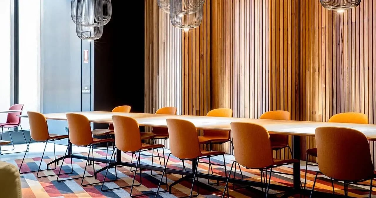 Orange chairs around a long table communal area at Iglu South Yarra in Melbourne Student Accommodation