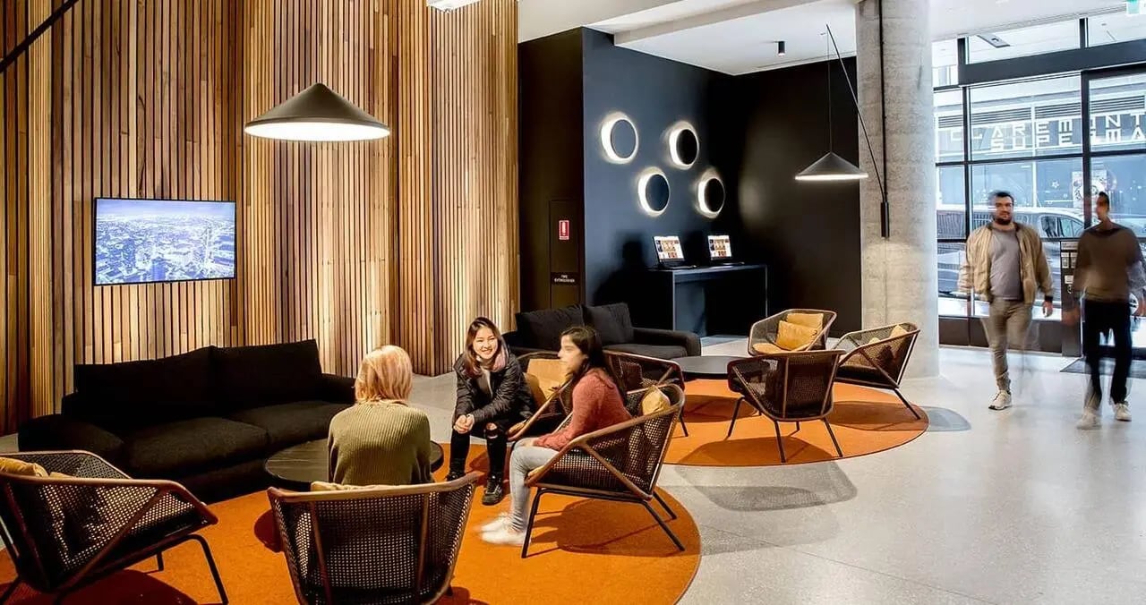 Students in modern lounge with sofas and chairs living room at Iglu South Yarra in Melbourne Student Accommodation