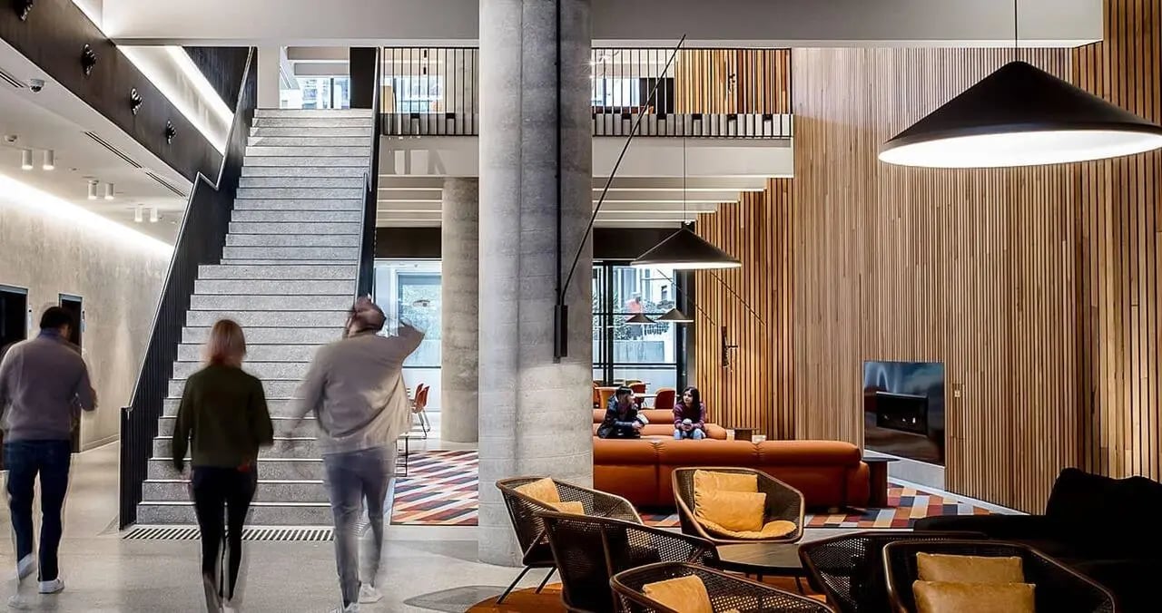 Stairs people couches chairs wood paneling communal area at Iglu South Yarra in Melbourne Student Accommodation