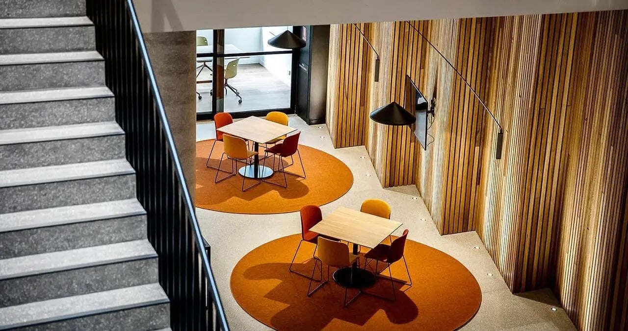 Two tables with chairs on orange rugs communal area at Iglu South Yarra in Melbourne Student Accommodation