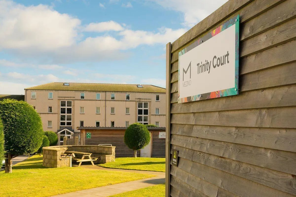 Sign and courtyard picnic table exterior at Trinity Court in Aberdeen Student Accommodation