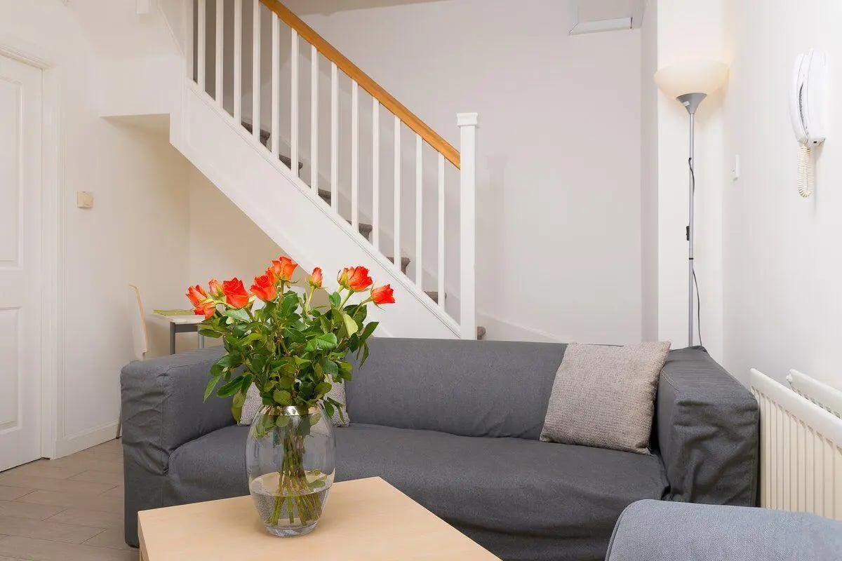 Gray sofa glass vase orange roses living room at Trinity Court in Aberdeen Student Accommodation