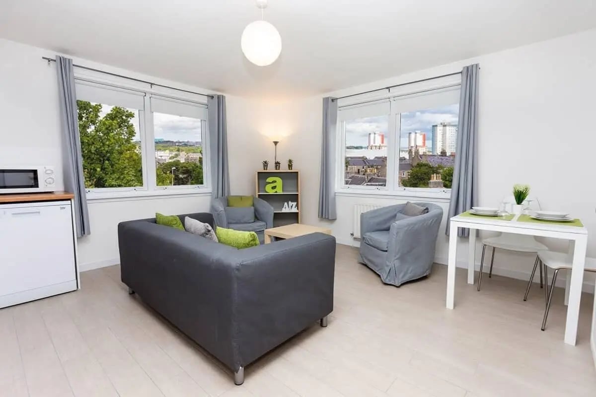Sofa chairs dining table and microwave living room at Trinity Court in Aberdeen Student Accommodation