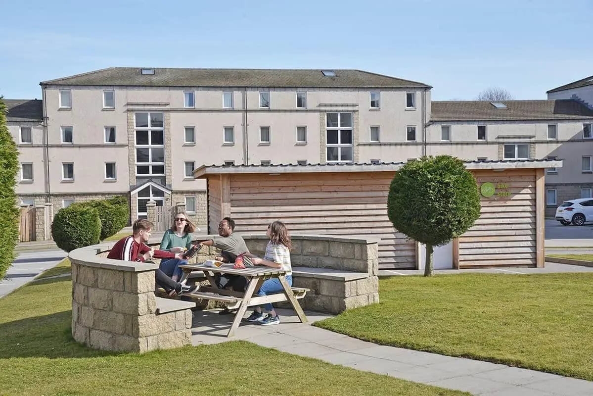 Students gathered at picnic table exterior living area at Trinity Court in Aberdeen Student Accommodation
