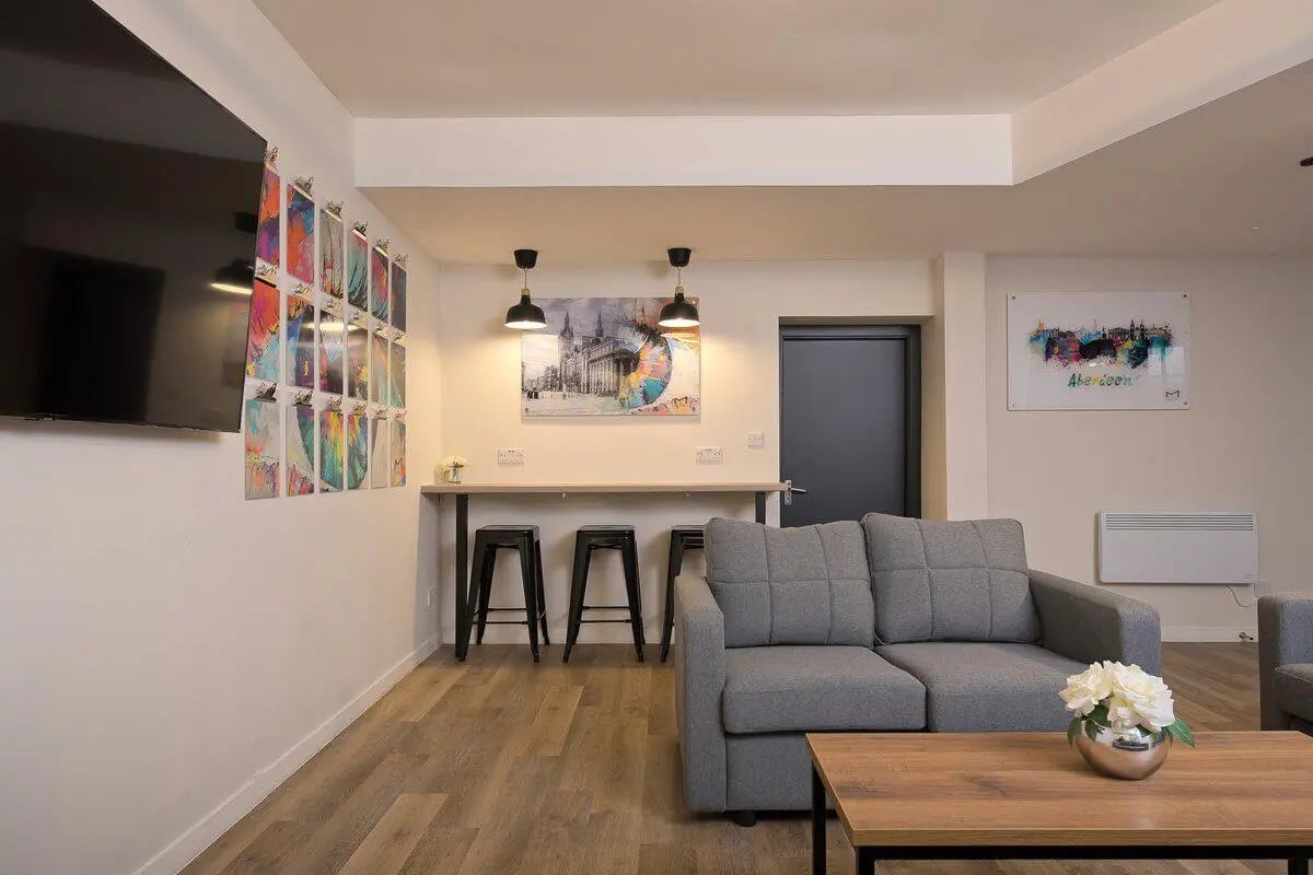 Grey sofa bar stools artwork and television living room at King Street 207 in Aberdeen Student Accommodation