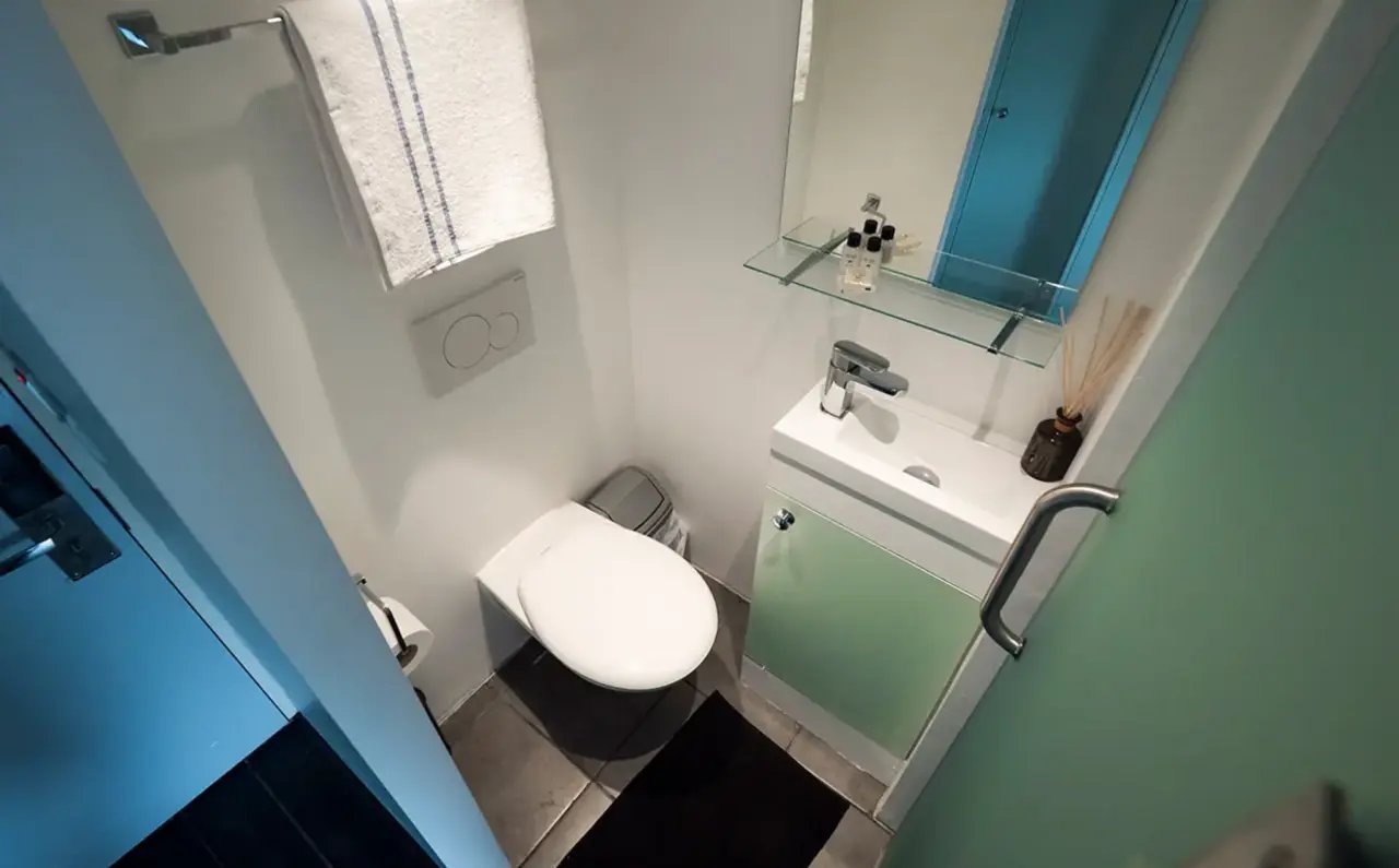 Toilet sink with green cabinet and towel bathroom at The Stay Club - Camden in London Student Accommodation