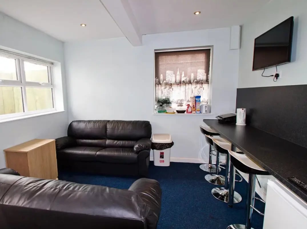 Black sofas bar stools and kitchen counter living room at Radmoor House in Loughborough Student Accommodation