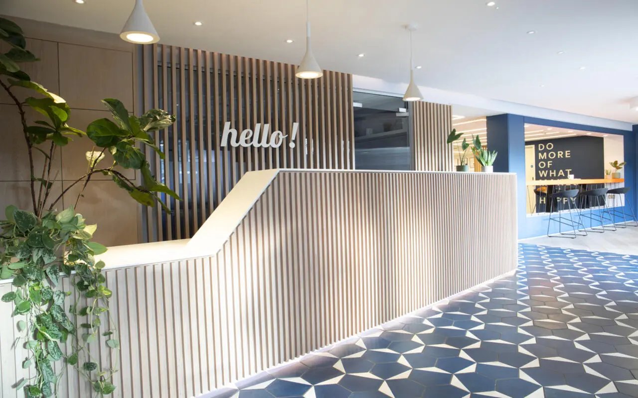 Hello reception desk with plants and blue floor reception area at Student Castle Cambridge in Cambridge Student Accommodation