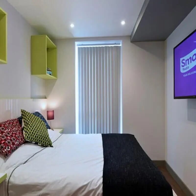 Bed with pillows shelves TV bedroom at The Courtyard Block B in Huddersfield Student Accommodation