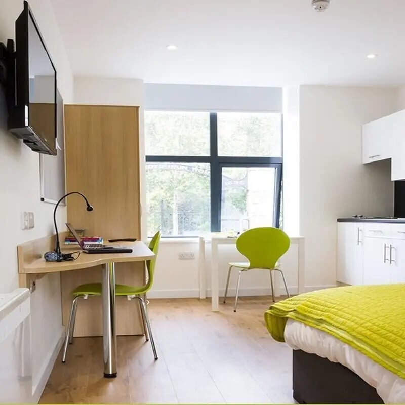 Desk with laptop chairs window kitchen living room at The Courtyard Block C in Huddersfield Student Accommodation