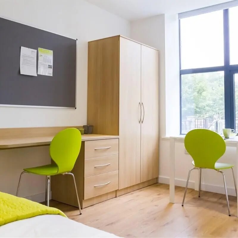 Desk wardrobe two chairs and a bed bedroom at The Courtyard Block C in Huddersfield Student Accommodation