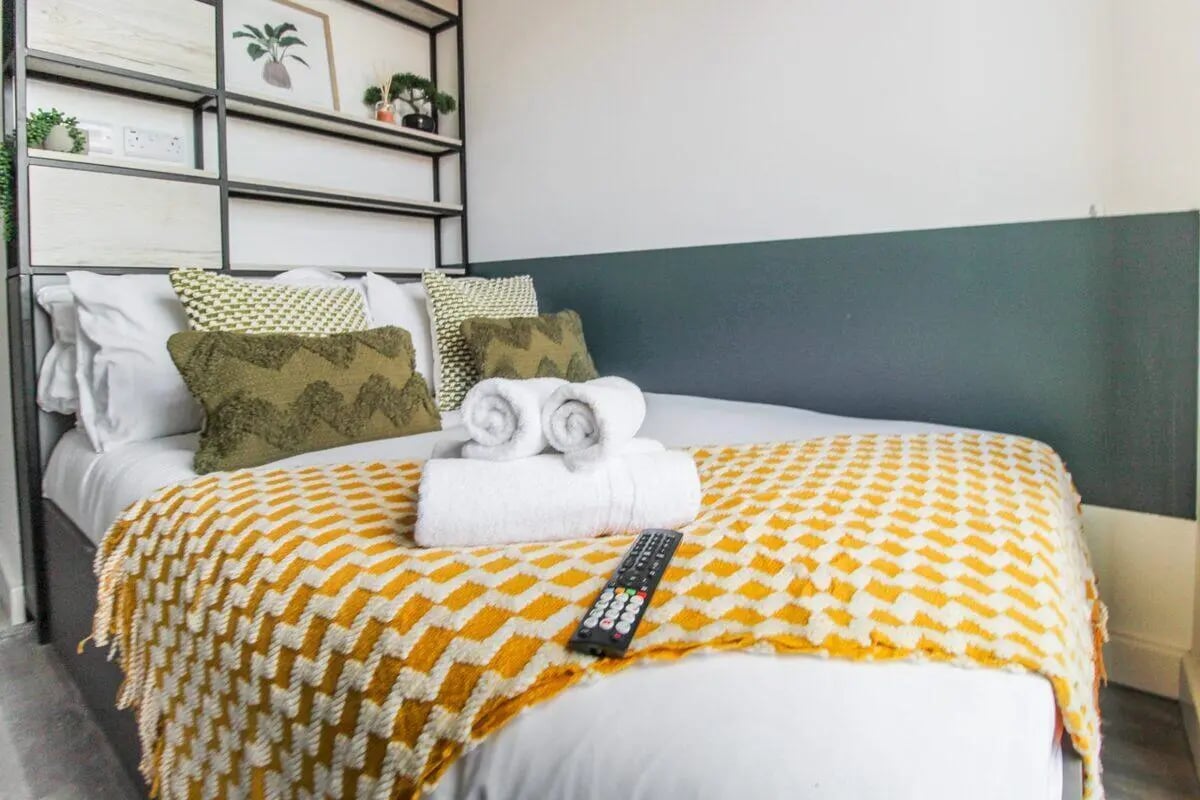 Bed with patterned throw towels and remote bedroom at The Nest Leicester in Leicester Student Accommodation