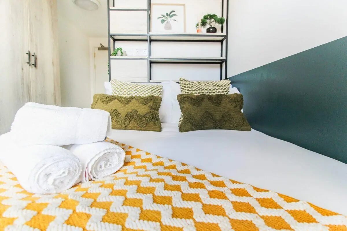 Bed with white towels green pillows yellow blanket Bedroom at The Nest Leicester in Leicester Student Accommodation