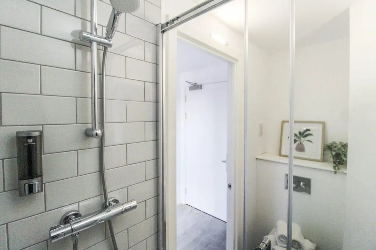 Shower dispenser white tile artwork bathroom at The Nest Leicester in Leicester Student Accommodation