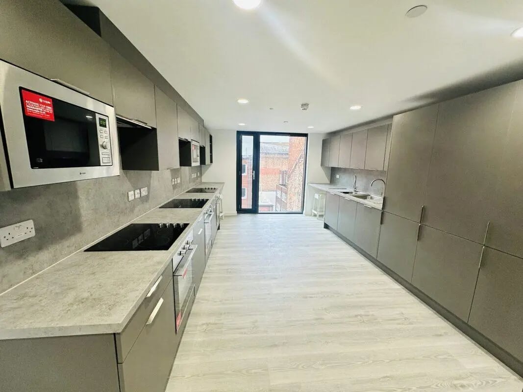Modern grey kitchen with stovetops ovens and microwave at The Nest Leicester in Leicester Student Accommodation