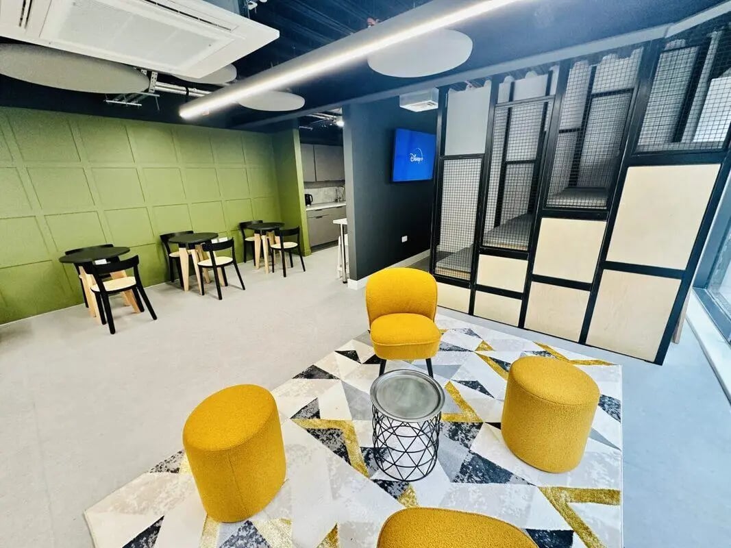 Yellow chairs stools rug tables and wall paneling common area at The Nest Leicester in Leicester Student Accommodation