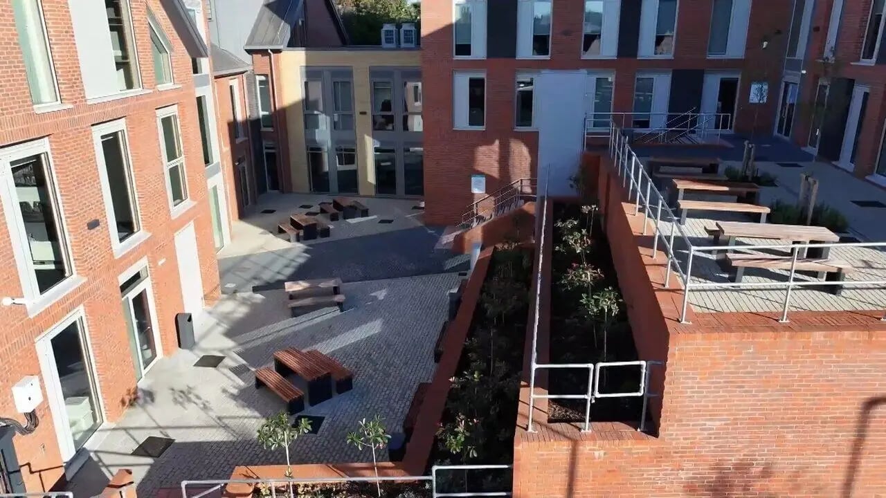 Brick buildings courtyard with wooden benches outdoor area at Albany Student Village in Coventry Student Accommodation