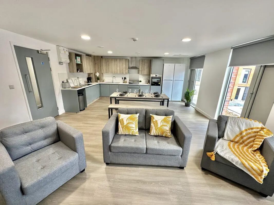 Two grey sofas and armchairs with kitchen living room at Albany Student Village in Coventry Student Accommodation