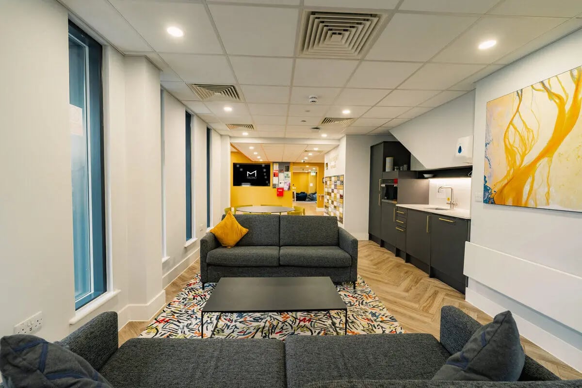 Grey sofas coffee table kitchen area living room at Hydrogen Falmouth in Falmouth Student Accommodation
