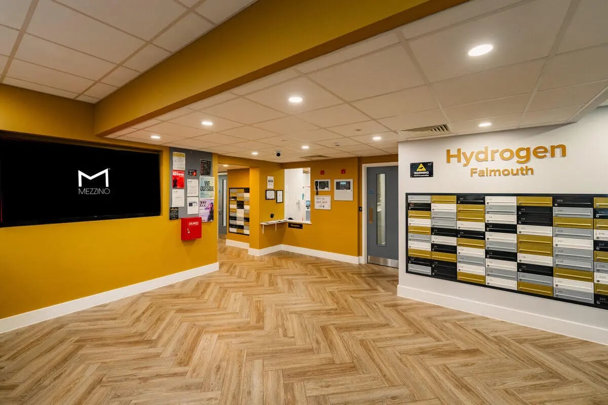 Mailboxes large screen and yellow walls reception area at Hydrogen Falmouth in Falmouth Student Accommodation