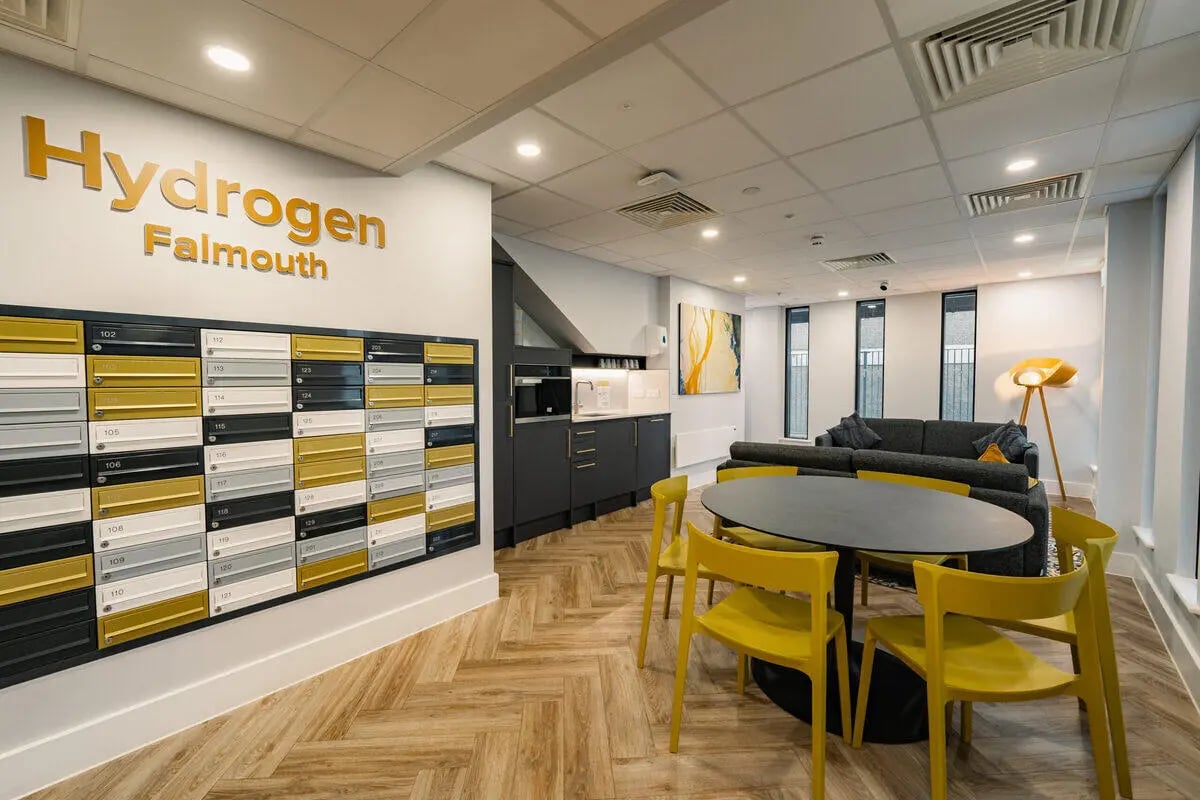 Mailboxes kitchen sofa round table yellow chairs communal area at Hydrogen Falmouth in Falmouth Student Accommodation