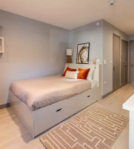 Bed with drawers orange pillows modern art bedroom at The Walls in Southampton Student Accommodation