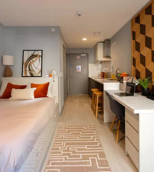 Bed with orange pillows and desk study area at The Walls in Southampton Student Accommodation
