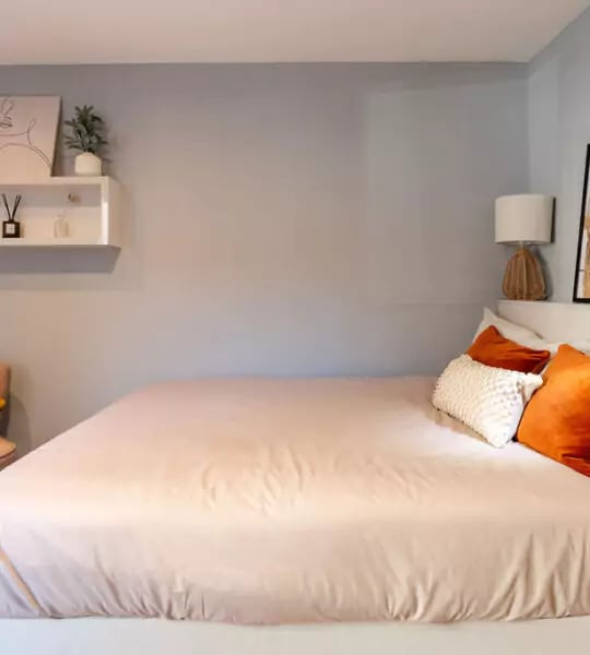 Bed with orange pillows shelf with plant bedroom at The Walls in Southampton Student Accommodation