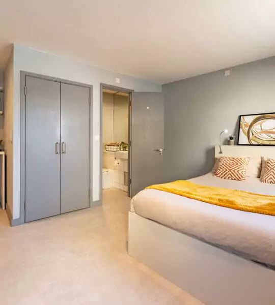 Bed with yellow throw open door to bathroom bedroom at The Walls in Southampton Student Accommodation