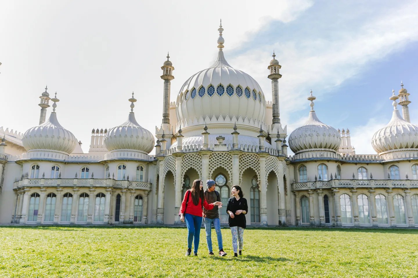 Three students walking on lawn near building exterior at Kaplan Living Brighton in Brighton Student Accommodation