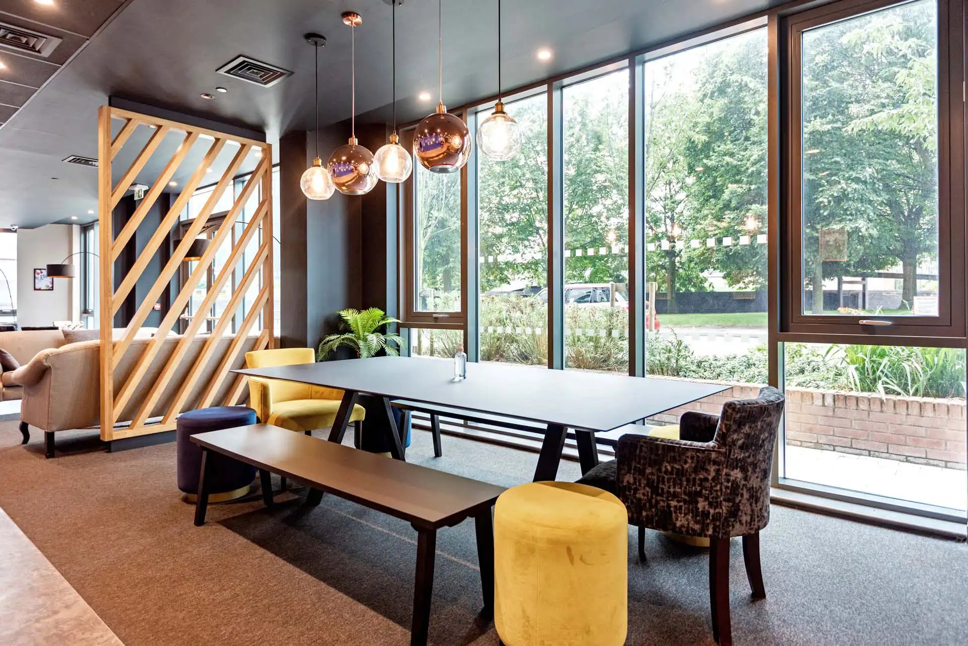 Dining table with benches chairs and ottoman common area at Trinity View Coventry in Coventry Student Accommodation