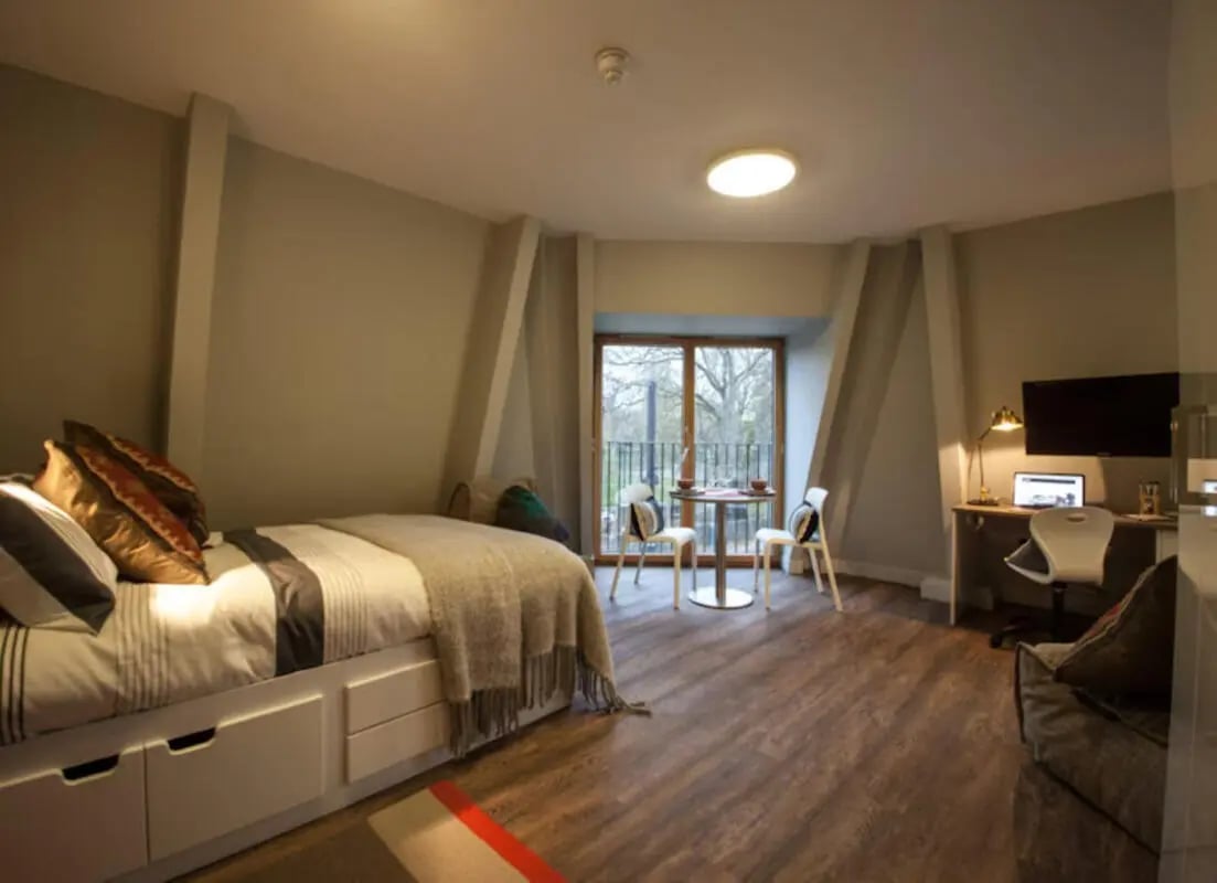 Bed with drawers desk with laptop and TV bedroom at Halsmere Studios in London Student Accommodation