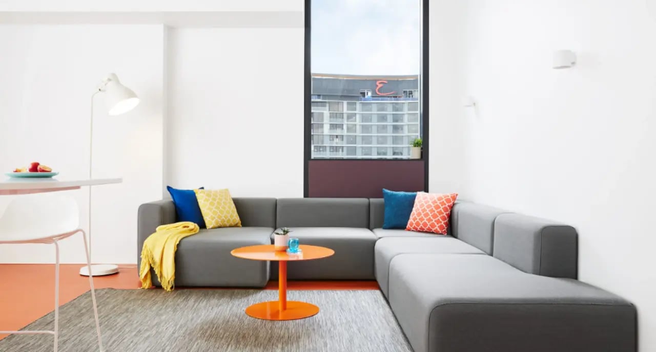 Sofa with cushions orange table and floor lamp Living room at Scape South Bank in Brisbane Student Accommodation