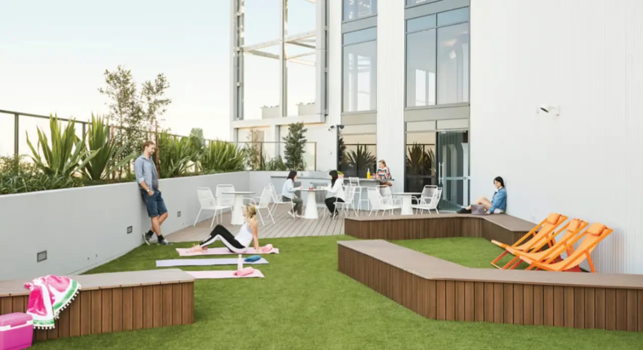 People relaxing on rooftop with seating and lounge chairs at Scape South Bank in Brisbane Student Accommodation