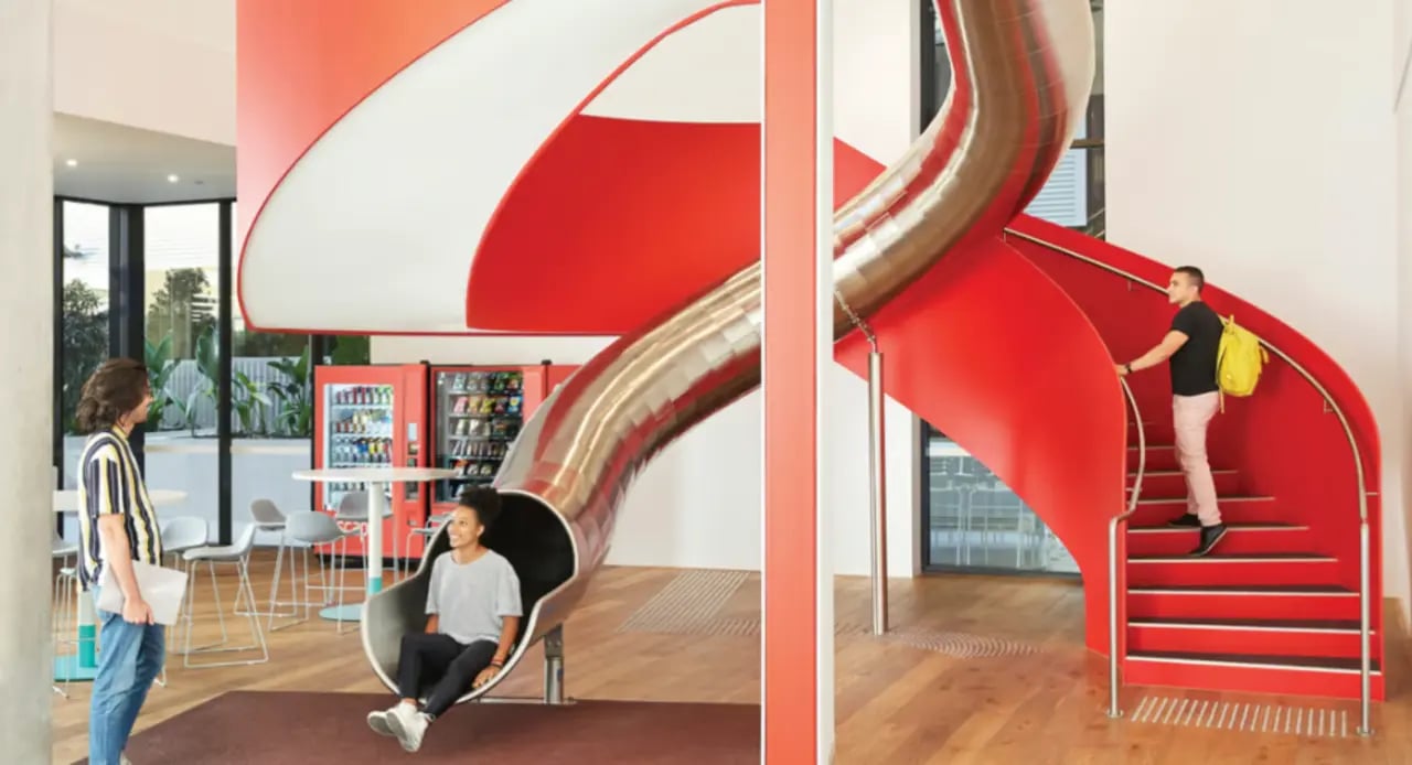 Red slide and spiral staircase with people common area at Scape South Bank in Brisbane Student Accommodation
