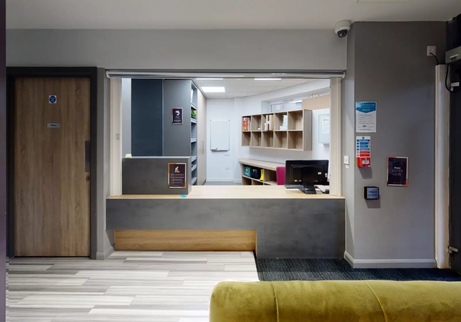 Reception desk with computer and shelves reception area at iQ Hayes Wharf in Lincoln Student Accommodation